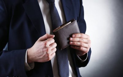 Leather wallet with money in male hands on dark background